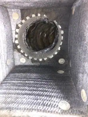 Interior view of a dust-filled air duct or ventilation shaft, with a circular metal vent or fan in the center and dust accumulation&mdash;highlighting the need for professional air duct services New Jersey to ensure clean, healthy airflow.