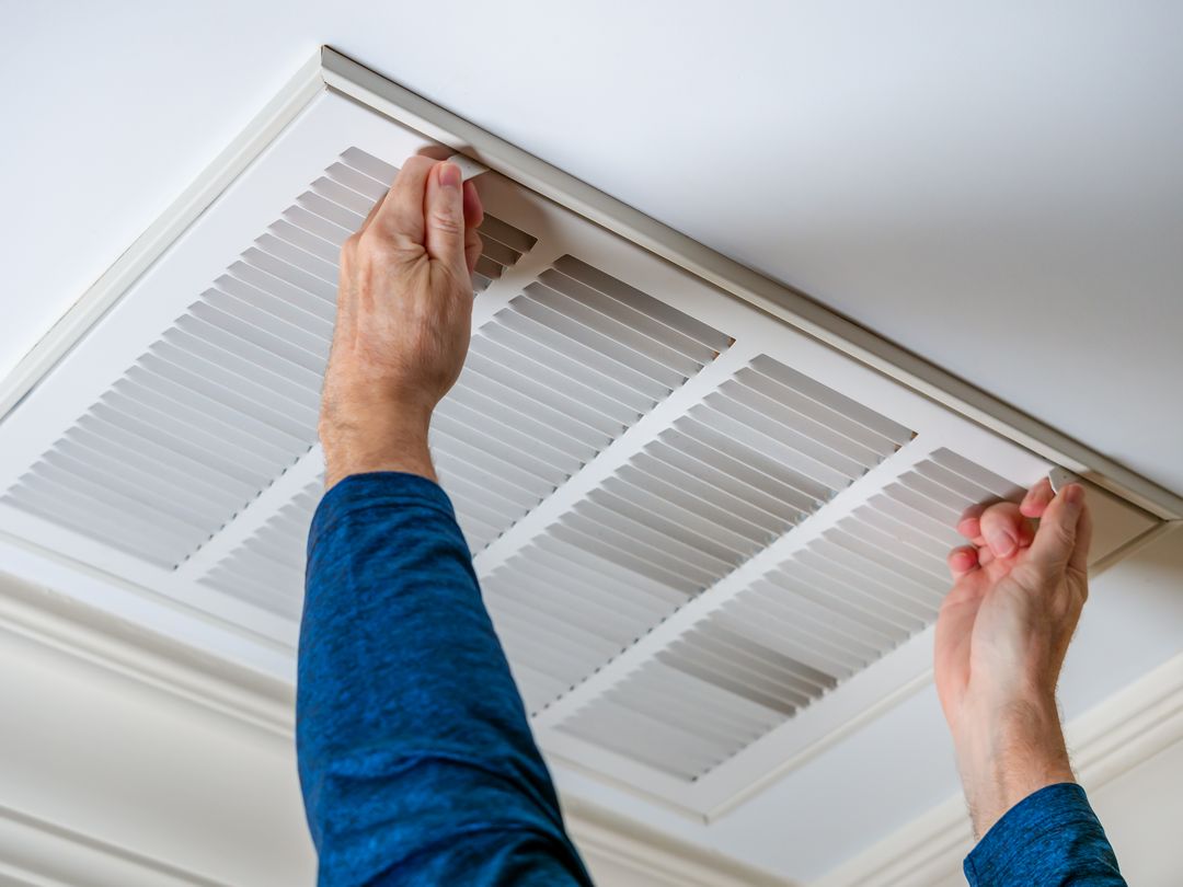 a man opening a ceiling air vent as part of the air duct cleaning and filter replacement process in New Jersey